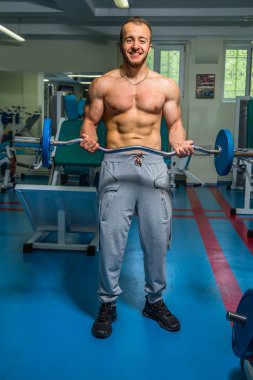 Kaslı adam spor salonunda ağırlık ile çalışma dışarı. Adam egzersizleri yapar.