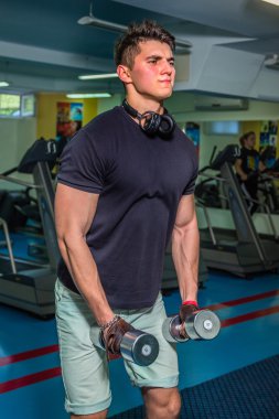 Vücut geliştirmeci yapar egzersiz jimnastik salonu dumbbells ile. İş ellerde kas söyle. Egzersiz programı sona yorucu. Fotoğraflar spor dergi ve Web siteleri için.
