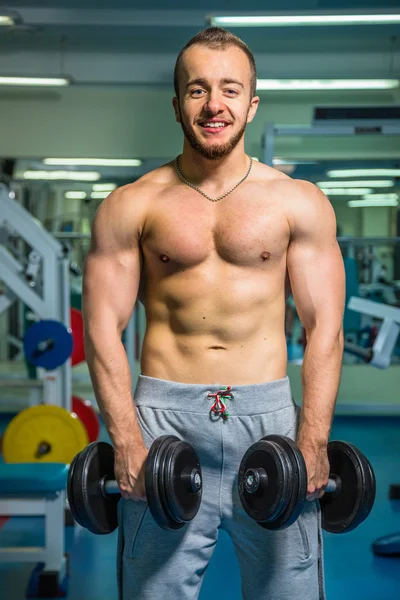 Man på gymmet. Man gör övningar hantlar. Sport, makt, hantlar, spänning, motion - konceptet med en hälsosam livsstil. Artikel om fitness och sport. — Stockfoto