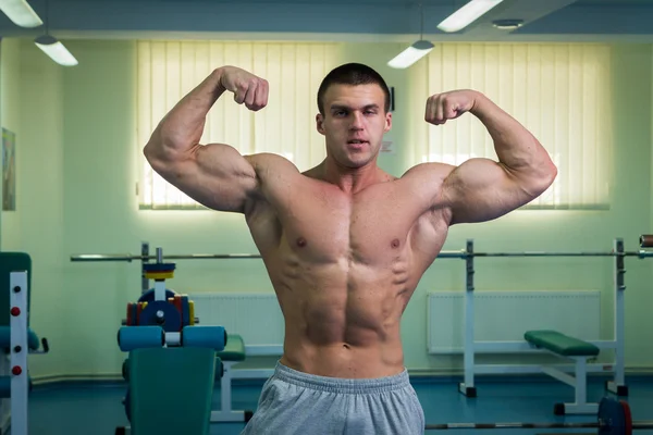 Hombre guapo, atlético y seguro en el gimnasio. postura culturismo — Foto de Stock