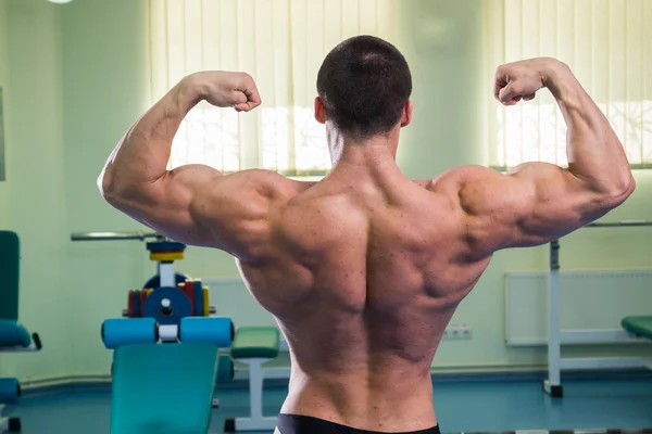 Un uomo bello, atletico e sicuro di se 'in palestra. Dimostra posa bodybuilding . — Foto Stock