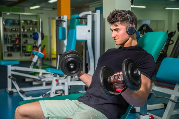 Bodybuilder makes exercise with dumbbells at the gym. Work on hands tell muscles. Exhausting workouts to an end. Photos for sporting magazines and websites. — Stock Photo, Image
