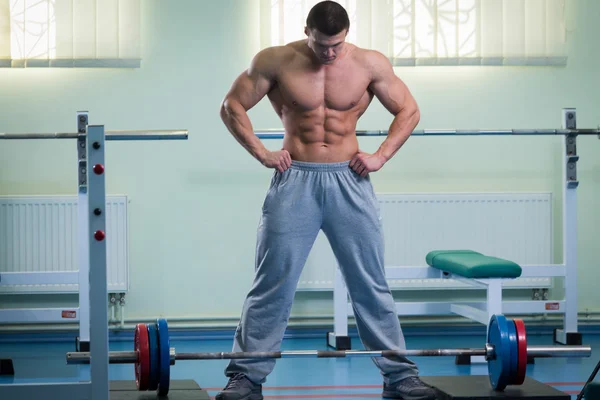 Beau, athlétique, confiant dans la salle de gym. Démontre la pose de musculation . — Photo