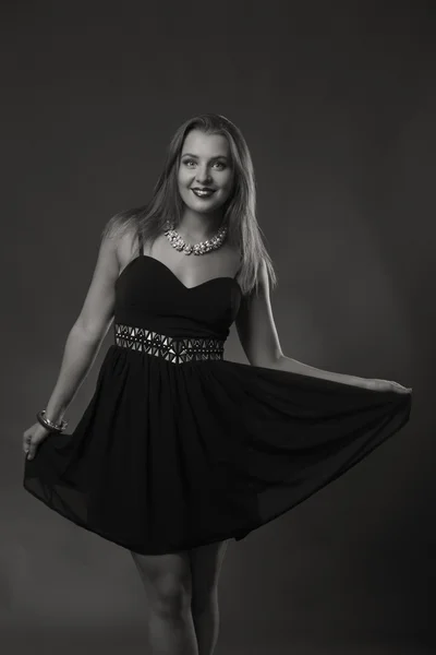 Verführerische Brünette in einem schönen stilvollen Kleid auf dunklem Hintergrund. — Stockfoto