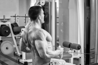 Jimnastik salonu kas adam. Kol kasları üzerinde çalışıyorum. Eğitim bir simülatör. Yorucu iş onun vücudunda.