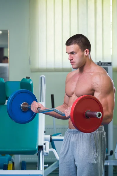 Mannen i gymmet pumpa buken muskler i en speciell simulator. — Stockfoto