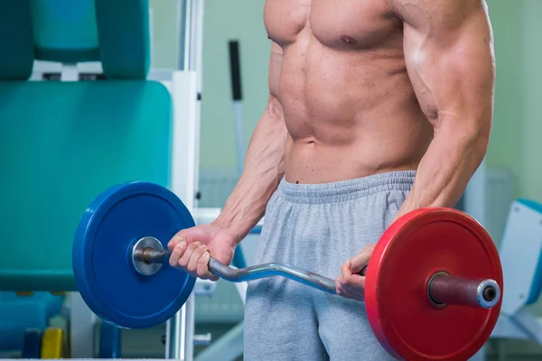 Mannen i gymmet pumpa buken muskler i en speciell simulator. — Stockfoto