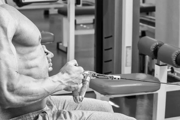 Homem musculoso no ginásio. Trabalhar nos músculos do braço. A treinar num simulador. Trabalho exaustivo em seu corpo . — Fotografia de Stock