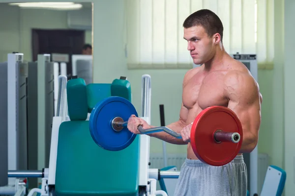 El hombre en el gimnasio bombeando músculos abdominales en un simulador especial . —  Fotos de Stock