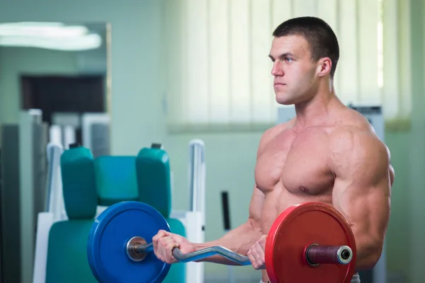 El hombre en el gimnasio bombeando músculos abdominales en un simulador especial . — Foto de Stock