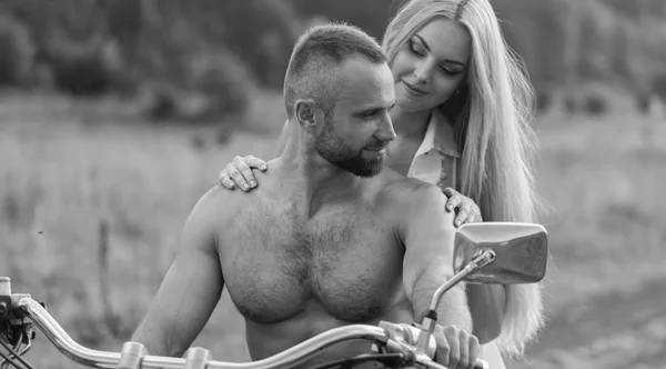 Una giovane coppia innamorata su una moto in un campo — Foto Stock
