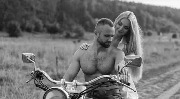 Um jovem casal apaixonado em uma motocicleta em um campo — Fotografia de Stock