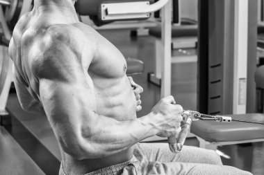 Jimnastik salonu kas adam. Kol kasları üzerinde çalışıyorum. Eğitim bir simülatör. Yorucu iş onun vücudunda.