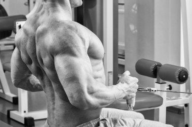 Jimnastik salonu kas adam. Kol kasları üzerinde çalışıyorum. Eğitim bir simülatör. Yorucu iş onun vücudunda.