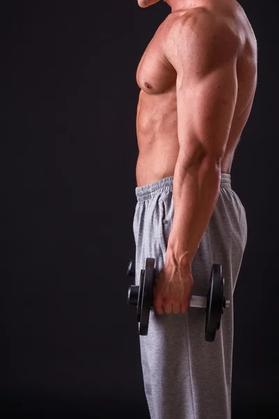 Fisiculturista posando em diferentes poses demonstrando seus músculos. Falha num fundo escuro. Homem mostrando músculos se esforçando. Bonito atleta corpo muscular . — Fotografia de Stock