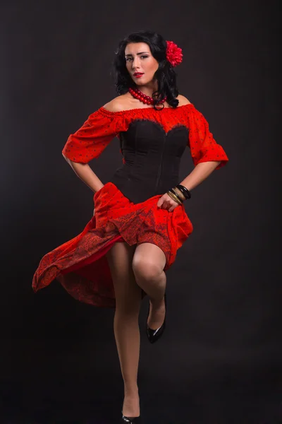 Hermosa mujer en un vestido rojo bailando sobre un fondo negro — Foto de Stock