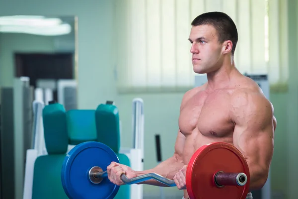 Człowiek w sali gimnastycznej pompowania brzucha mięśnie w specjalnym symulatorze. — Zdjęcie stockowe