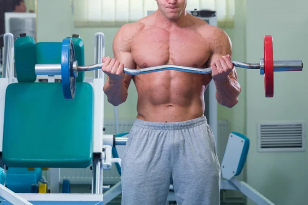 Mannen i gymmet pumpa buken muskler i en speciell simulator. — Stockfoto