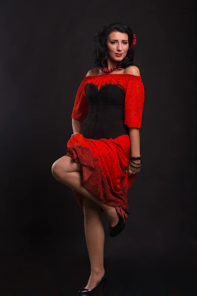 Hermosa mujer en un vestido rojo bailando sobre un fondo negro — Foto de Stock