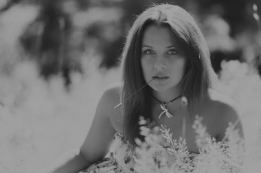 Beyaz elbiseli genç esmer kadın. Bir kız, güneşli bir günde pembe çiçekler tarlanın ortasında duruyor. Alan, çiçekler güzellik, doğa, - ülke tatil kavramı. Tatil hakkında makale.