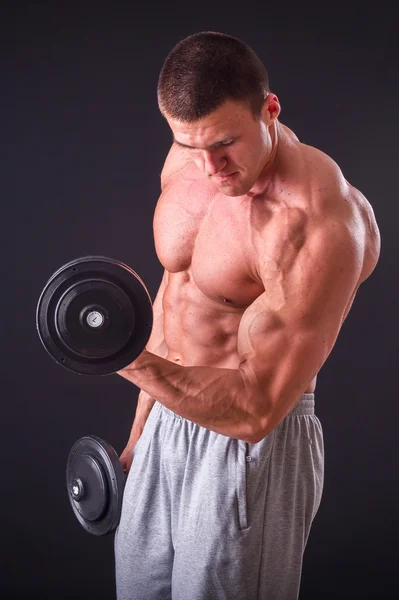 Bodybuilder poseren in verschillende poses aan te tonen hun spieren. Storing op een donkere achtergrond. Mannelijke weergegeven: spieren spannen. Mooi gespierd lichaam atleet. — Stockfoto