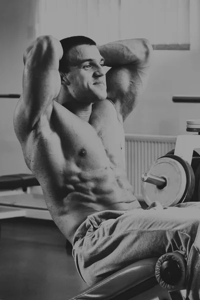 Muscular man in the gym. Work on the arm muscles. Training on a simulator. Exhausting work on his body. — Stock Photo, Image