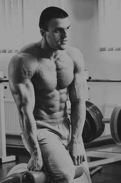 Muskularny mężczyzna w sali gimnastycznej. Działa na mięśnie ramion. Szkolenia na symulatorze. Wyczerpująca praca na ciele. — Zdjęcie stockowe