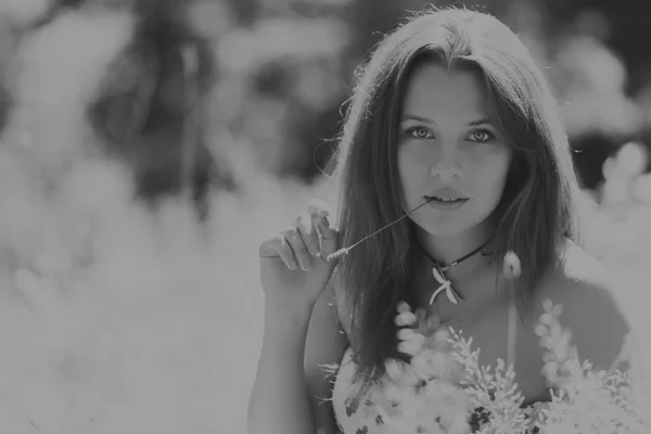 Mulher morena jovem em um vestido branco. Uma menina fica no meio do campo de flores cor-de-rosa em um dia ensolarado. Campo, flores beleza, natureza, - O conceito de férias no campo. Artigo sobre férias . — Fotografia de Stock