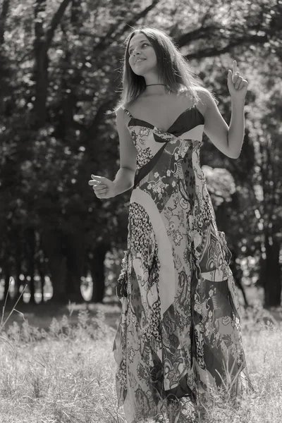 Mladá bruneta žena v bílých šatech. Dívka stojí uprostřed růžové květy pole za slunečného dne. Pole, květiny krása, příroda, - koncept zemi dovolenou. Článek o dovolené. — Stock fotografie
