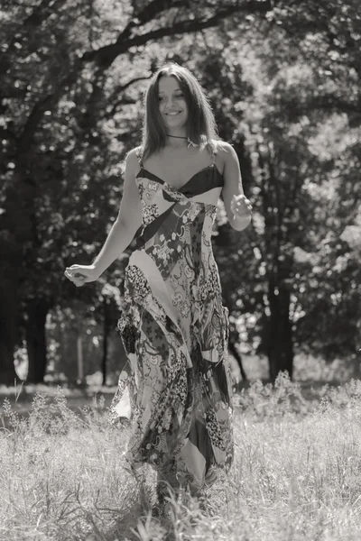 Jonge brunette vrouw in een witte jurk. Een meisje staat in het midden van de roze bloemen veld op een zonnige dag. Veld bloemen schoonheid, natuur, -het concept van land vakantie. Artikel over vakantie. — Stockfoto