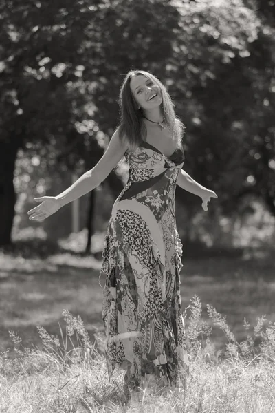 Giovane donna bruna in un vestito bianco. Una ragazza si trova in mezzo al campo di fiori rosa in una giornata di sole. Campo, la bellezza dei fiori, la natura, - Il concetto di vacanza in campagna. Articolo sulle vacanze . — Foto Stock