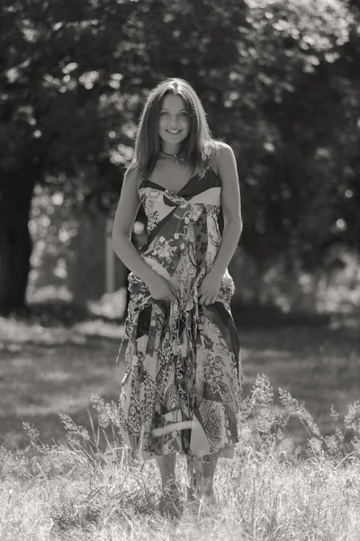 Jeune femme brune en robe blanche. Une fille se tient au milieu du champ de fleurs roses par une journée ensoleillée. Champ, fleurs beauté, nature, - Le concept de vacances à la campagne. Article sur les vacances . — Photo