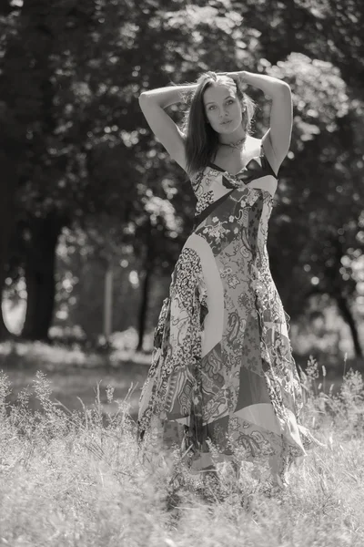 Mulher morena jovem em um vestido branco. Uma menina fica no meio do campo de flores cor-de-rosa em um dia ensolarado. Campo, flores beleza, natureza, - O conceito de férias no campo. Artigo sobre férias . — Fotografia de Stock