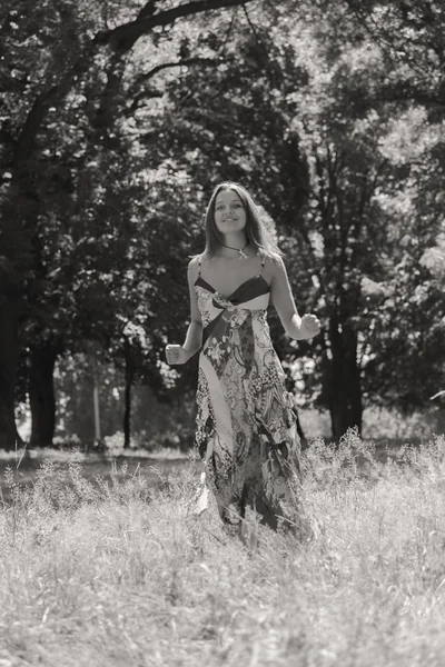 Mujer morena joven en un vestido blanco. Una chica está parada en medio del campo de flores rosadas en un día soleado. Campo, flores belleza, naturaleza, - El concepto de vacaciones en el campo. Artículo sobre vacaciones . —  Fotos de Stock