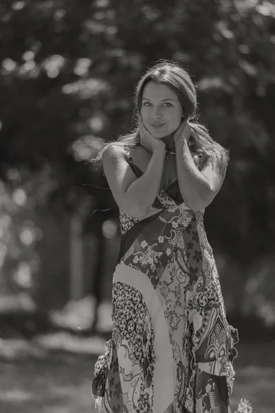 Junge brünette Frau in einem weißen Kleid. Ein Mädchen steht an einem sonnigen Tag inmitten eines rosafarbenen Blumenfeldes. Feld, Blumen Schönheit, Natur - das Konzept des Landurlaubs. Artikel über Urlaub. — Stockfoto