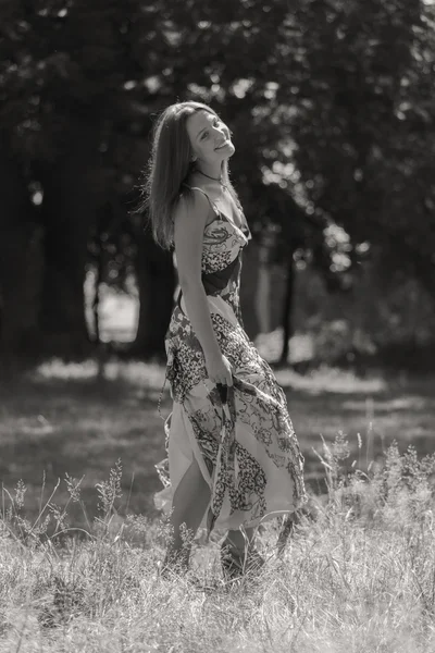 Jonge brunette vrouw in een witte jurk. Een meisje staat in het midden van de roze bloemen veld op een zonnige dag. Veld bloemen schoonheid, natuur, -het concept van land vakantie. Artikel over vakantie. — Stockfoto