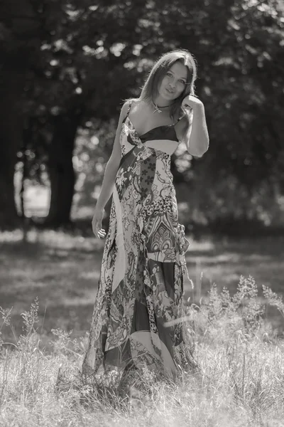 Mujer morena joven en un vestido blanco. Una chica está parada en medio del campo de flores rosadas en un día soleado. Campo, flores belleza, naturaleza, - El concepto de vacaciones en el campo. Artículo sobre vacaciones . — Foto de Stock