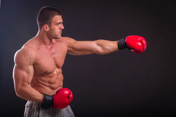 Bodybuilder poserar i olika poser visar sina muskler. Fel på en mörk bakgrund. Manliga visar musklerna spännare. Vackra muskulös kropp idrottsman nen. — Stockfoto