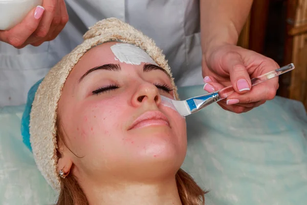 Tratamentos de beleza para a pele problema. A menina no salão de spa, aplicando creme . — Fotografia de Stock