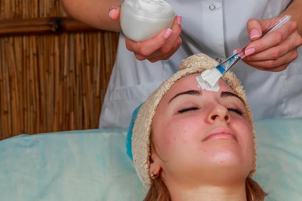 Tratamentos de beleza para a pele problema. A menina no salão de spa, aplicando creme . — Fotografia de Stock