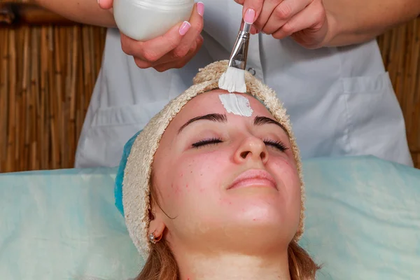 Косметические процедуры для проблемной кожи. Девушка в спа-салоне, наносит крем . — стоковое фото