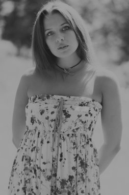 Beyaz elbiseli genç esmer kadın. Bir kız, güneşli bir günde pembe çiçekler tarlanın ortasında duruyor. Alan, çiçekler güzellik, doğa, - ülke tatil kavramı. Tatil hakkında makale.