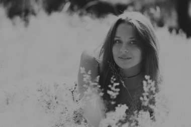 Beyaz elbiseli genç esmer kadın. Bir kız, güneşli bir günde pembe çiçekler tarlanın ortasında duruyor. Alan, çiçekler güzellik, doğa, - ülke tatil kavramı. Tatil hakkında makale.