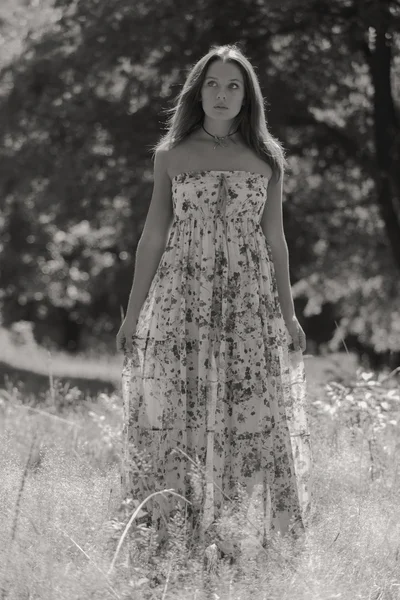 Jonge brunette vrouw in een witte jurk. Een meisje staat in het midden van de roze bloemen veld op een zonnige dag. Veld bloemen schoonheid, natuur, -het concept van land vakantie. Artikel over vakantie. — Stockfoto