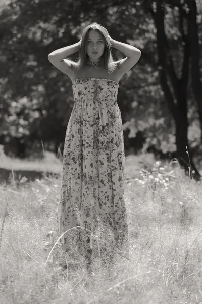 Junge brünette Frau in einem weißen Kleid. Ein Mädchen steht an einem sonnigen Tag inmitten eines rosafarbenen Blumenfeldes. Feld, Blumen Schönheit, Natur - das Konzept des Landurlaubs. Artikel über Urlaub. — Stockfoto