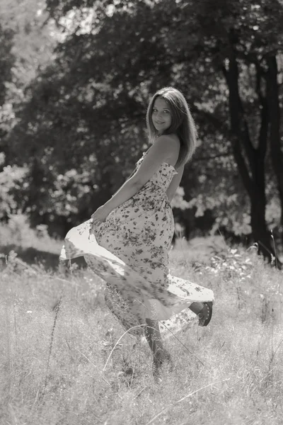 Mulher morena jovem em um vestido branco. Uma menina fica no meio do campo de flores cor-de-rosa em um dia ensolarado. Campo, flores beleza, natureza, - O conceito de férias no campo. Artigo sobre férias . — Fotografia de Stock