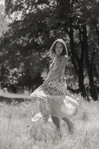 Mujer morena joven en un vestido blanco. Una chica está parada en medio del campo de flores rosadas en un día soleado. Campo, flores belleza, naturaleza, - El concepto de vacaciones en el campo. Artículo sobre vacaciones . — Foto de Stock