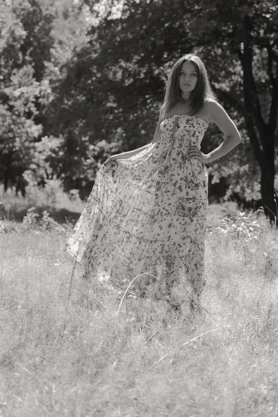 Jonge brunette vrouw in een witte jurk. Een meisje staat in het midden van de roze bloemen veld op een zonnige dag. Veld bloemen schoonheid, natuur, -het concept van land vakantie. Artikel over vakantie. — Stockfoto