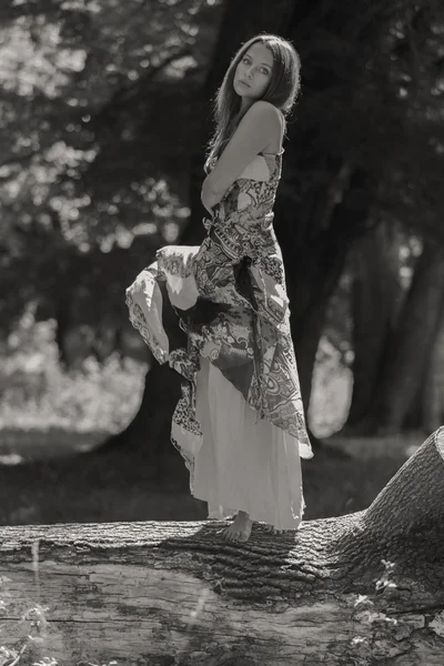 Junge brünette Frau in einem weißen Kleid. Ein Mädchen steht an einem sonnigen Tag inmitten eines rosafarbenen Blumenfeldes. Feld, Blumen Schönheit, Natur - das Konzept des Landurlaubs. Artikel über Urlaub. — Stockfoto