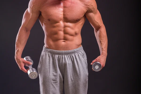 Fisiculturista posando em diferentes poses demonstrando seus músculos. Falha num fundo escuro. Homem mostrando músculos se esforçando. Bonito atleta corpo muscular . — Fotografia de Stock